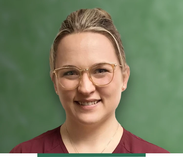 Smiling woman with glasses in front of green background.